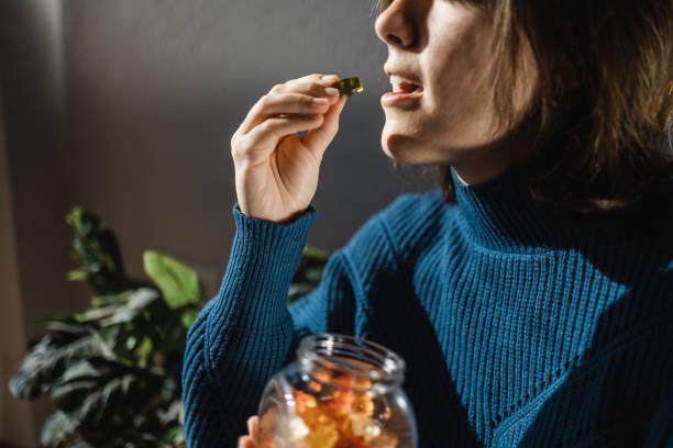 Cbd cannabis gummy - Woman eating edible weed sweet candy leaf for anxiety alternative treatment - Medical marijuana Cbd cannabis gummy - Woman eating edible weed sweet candy leaf for anxiety alternative treatment - Medical marijuana CBD gummies stock pictures, royalty-free photos & images